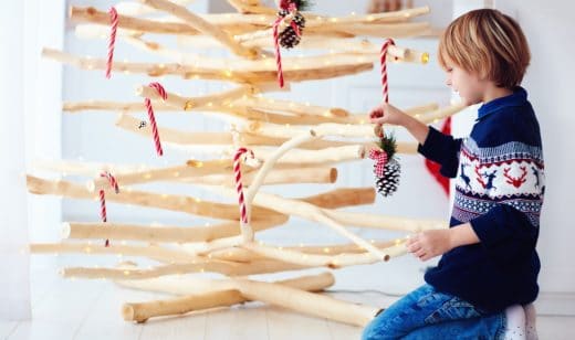 enfant décorant un sapin en bois